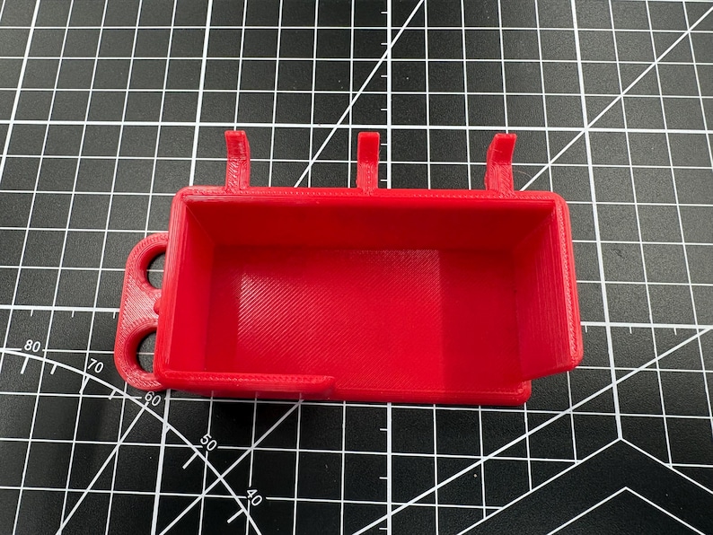 Top-down view of the red multimeter holder on a grid mat, highlighting the spacious internal storage area and integrated probe management loops.