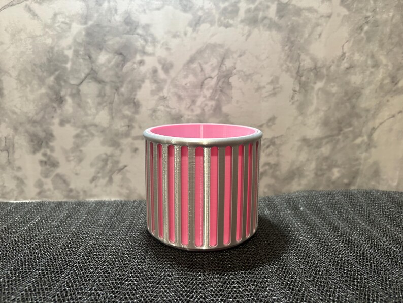 A minimalist silver ribbed tool holder with a bright pink interior, showcasing a smooth 3D printed finish and geometric lines.