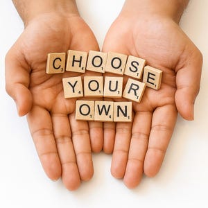 Può includere: Un paio di mani tiene tessere di legno con la scritta "CHOOSE YOUR OWN". Le tessere beige hanno lettere e numeri neri, che formano un messaggio motivazionale. Lo sfondo è una superficie bianca.