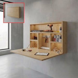 Puede incluir: Un escritorio de madera clara montado en la pared con múltiples compartimentos de almacenamiento y una superficie de trabajo plegable. El escritorio está montado en una pared gris e incluye una variedad de herramientas y suministros.