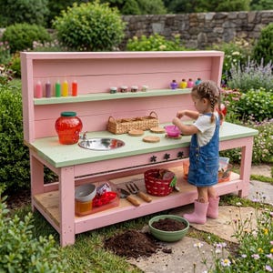 Puede incluir: Una cocina de juguete de madera rosa y verde con un fregadero de acero inoxidable, estantes y varios accesorios. La cocina incluye un tarro rojo, botellas de colores y una pequeña cesta. Un niño está jugando con la cocina.