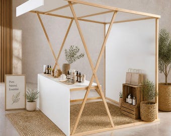 May include: A white and wood-framed booth displays natural skincare products. The booth has a white countertop and a woven rug. A sign reads "Pure. Natural. Essential." with a leaf illustration. Plants and paper bags add to the display.