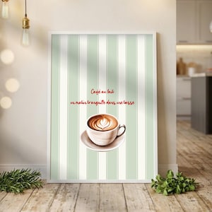 May include: A framed print featuring a cup of coffee with latte art on a saucer, set against a striped background of white and light green. The text "Café au lait, un matin tranquille dans une tasse" is written in red.