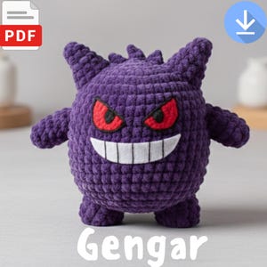 May include: A handmade purple crochet Gengar plushie with red eyes and a wide white smile. The plushie has small arms and legs, and a spiky head. The word "Gengar" is written in white at the bottom of the image.