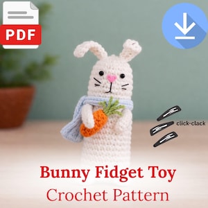 May include: A white crochet bunny fidget toy with a light blue scarf and an orange carrot. The bunny has black eyes and whiskers, and a pink nose. The image includes the text "Bunny Fidget Toy Crochet Pattern".