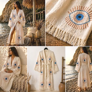 May include: Cream-colored robe with an embroidered eye design in blue and orange. The robe has a belt, wide sleeves, and fringe along the bottom. The eye design is repeated on the sleeves and back. The robe is made of a lightweight fabric.