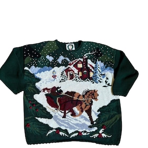 Könnte beinhalten: Ein dunkelgrüner Langarm-Strickpullover mit einer Winterszene, die einen Pferdeschlitten, ein rotes Haus mit Schornstein, verschneiten Boden und Tannenbäume zeigt. Das Design enthält kleine rote Beerenakzente am unteren Saum.