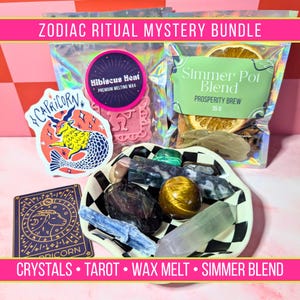 May include: A Zodiac Ritual Mystery Bundle with crystals, tarot cards, wax melts, and simmer blend. The bundle includes a Capricorn sticker and tarot card, a pink wax melt, and a simmer pot blend. A black and white checkered bowl holds various crystals.