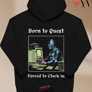 May include: Black hoodie with the text "Born to Quest" above a graphic of a knight at a computer, and "Forced to Clock In" below. The graphic is in a white box. The hoodie has a drawstring hood and a kangaroo pocket.