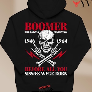 Könnte beinhalten: Schwarzer Kapuzenpullover mit Totenkopf-Grafik, gekreuzten Knochen und dem Text "BOOMER THE BADASS GENERATION 1946-1964." Das Design umfasst Blitze und den Satz "BEFORE ALL YOU SISSIES WERE BORN."