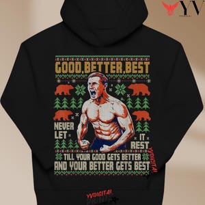 May include: Black hooded sweatshirt with a graphic design. The design features a muscular man, bears, trees, and the text "GOOD, BETTER, BEST", "NEVER LET", and "IT REST". The sweatshirt is a comfortable and stylish garment.