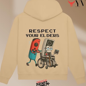 May include: Beige hoodie with a graphic of a red and blue video game controller pushing an older controller in a wheelchair. The text "RESPECT YOUR ELDERS" is above the graphic.