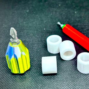 May include: A multi-coloured screwdriver with a silver tip, a red handle, and four white cylindrical objects. The screwdriver's handle is yellow, blue, and green. The red handle has a textured grip.