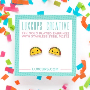 May include: A pair of gold-plated taco earrings with stainless steel posts. The earrings are on a white background with confetti.
