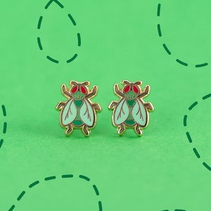 May include: A pair of gold-tone earrings featuring a green and red fly design.