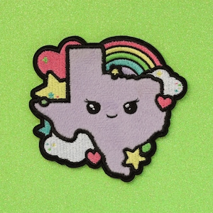 May include: A purple felt patch shaped like the state of Texas with a smiling face, rainbow, stars, and clouds.