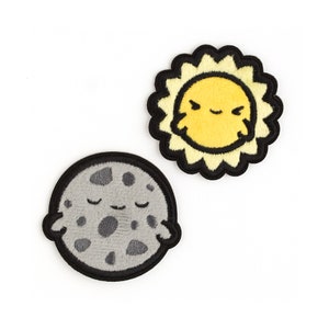 May include: Two embroidered patches, one of a yellow sun with a smiling face and the other of a gray moon with a sleeping face.