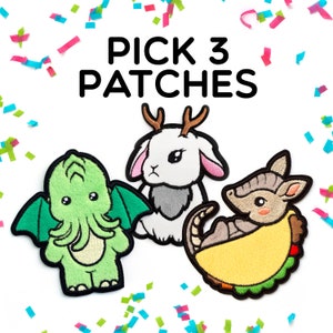 May include: Three embroidered patches featuring a green creature with wings, a white rabbit with brown antlers, and an armadillo inside a yellow taco shell. The text PICK 3 PATCHES is printed in black above the patches on a white background.