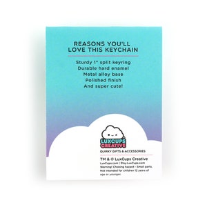 May include: A blue and pink card with the text "Reasons you'll love this keychain" and a list of features: Sturdy 1" split keyring, Durable hard enamel, Metal alloy base, Polished finish, And super cute!  The card also features a cartoon cloud with a face and the text "LuxCups Creative" and "Quirky Gifts & Accessories".  The card also includes the text "TM & &copy; LuxCups Creative" and "LuxCups.com | Etsy.LuxCups.com".