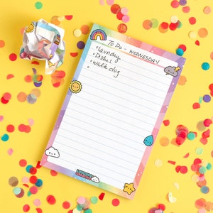 May include: A rainbow-colored notepad with a to-do list for Wednesday. The list includes laundry, dishes, and walk dog. The notepad is decorated with cute cartoon characters and is surrounded by colorful confetti.
