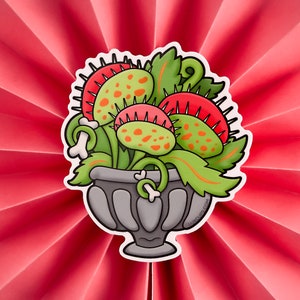 May include: A cartoon illustration of a group of Venus flytraps in a gray pot with bone-like handles. The flytraps are green with red and orange spots and have sharp teeth.