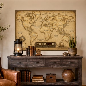 Op de afbeelding: Een rechthoekige wandkunstprint met een wereldkaart in vintage-stijl op een sepia-kleurige achtergrond. De kaart toont continenten, oceanen en landen met tekstlabels, inclusief de titel THE WORLD EXPLORE DISCOVER ADVENTURE.