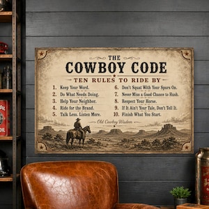 May include: A rectangular wall sign featuring the text The Cowboy Code Ten Rules to Ride By and Old Cowboy Wisdom. The design includes a sepia-toned illustration of a lone cowboy on horseback in a desert landscape with mesas and mountains.
