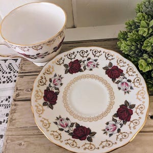 Puede incluir: Juego de taza y platillo de t&eacute; vintage. La taza y el platillo de porcelana blanca presentan un patr&oacute;n floral de rosas en burdeos y rosa, con ribete dorado. El platillo tiene un borde festoneado y un dise&ntilde;o de filigrana dorada.