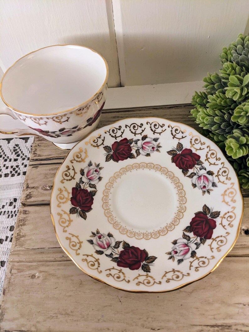 Puede incluir: Juego de taza y platillo de t&eacute; vintage. La taza y el platillo de porcelana blanca presentan un patr&oacute;n floral de rosas en burdeos y rosa, con ribete dorado. El platillo tiene un borde festoneado y un dise&ntilde;o de filigrana dorada.