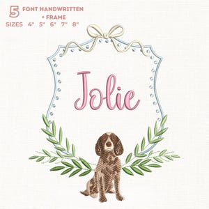 Könnte beinhalten: Ein gesticktes Design mit dem Namen "Jolie" in rosa Schrift in einem hellblauen Rahmen, verziert mit einer Schleife und einer Hundeillustration. Das Design umfasst grüne Blätter und Größen von 10 cm bis 20 cm.