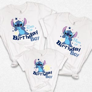 K&ouml;nnte beinhalten: Drei wei&szlig;e T-Shirts mit einem blauen Cartoon-Charakter-Design. Die Shirts tragen die Aufschriften "Dad of Birthday Boy", "Mom of Birthday Boy" und "Birthday Boy" in Blau. Das Design umfasst Sterne und einen gelben Mond.