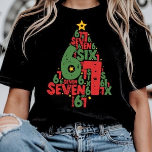 May include: Black t-shirt with a Christmas tree design. The tree is made up of the numbers 6, 7, and the words "six" and "seven" in red and green. A yellow star is at the top of the tree.
