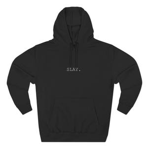 Op de afbeelding: Zwarte hoodie met een voorzak en trekkoord. Het woord "SLAY." is in kleine, witte hoofdletters op de borst gedrukt. De hoodie heeft lange mouwen en een capuchon.