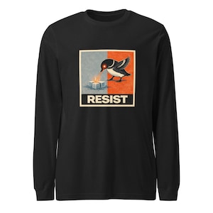 May include: Black long-sleeve shirt featuring a graphic of a bird with a red eye, positioned above a cube, with the word "RESIST" in a white font. The bird is black and white, set against a red and blue background.