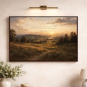 May include: A rectangular landscape wall art print featuring a sunset over a rolling meadow with trees and a distant river. The text reads: You make known to me the path of life; you will fill me with joy in your presence. Psalm 16:11.