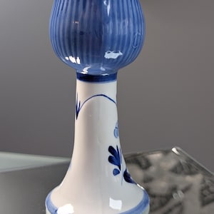 May include: A blue and white ceramic tulip-shaped vase. The vase has a flared base and a long, slender neck. The top of the vase is shaped like a tulip, with vertical ridges. The vase is decorated with blue floral designs.