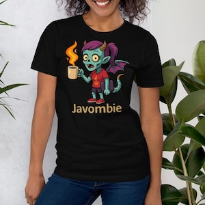 Op de afbeelding: Zwart t-shirt met een cartoon "Javombie" ontwerp. De illustratie toont een zombie met een turquoise huid, paars haar en hoorns, die een koffiemok met vlammen vasthoudt. De tekst "Javombie" is in goud gedrukt.