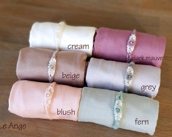 May include: Six rolled up fabric swatches in various colors, including cream, beige, blush, grey, dark mauve, and fern. Each swatch has a decorative lace trim with a pearl accent.