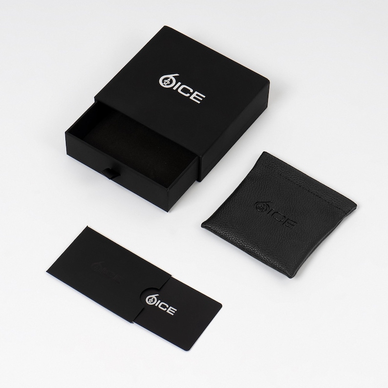 K&ouml;nnte beinhalten: Eine schwarze Geschenkbox mit dem Wort &bdquo;ICE&ldquo; in Wei&szlig;, ein schwarzes Etui und eine schwarze Karte. Die Box ist ge&ouml;ffnet und zeigt einen leeren Innenraum. Das Etui und die Karte tragen ebenfalls das &bdquo;ICE&ldquo;-Logo. Alles liegt auf wei&szlig;em Untergrund.