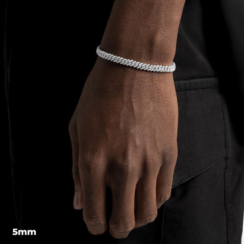 K&ouml;nnte beinhalten: Ein silbernes Armband mit einer Breite von 5 mm wird am Handgelenk einer Person getragen. Das Armband hat ein Gliederdesign und besteht aus einem gl&auml;nzenden, reflektierenden Material. Die Person tr&auml;gt ein schwarzes Oberteil.