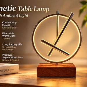 Op de afbeelding: Een kinetische tafellamp met een cirkelvormig metalen frame met een geïntegreerde warme LED-lichtstrip, twee roterende metalen armen en een rechthoekige voet van sapelihout. De tekst op de afbeelding luidt: Kinetic Table Lamp.