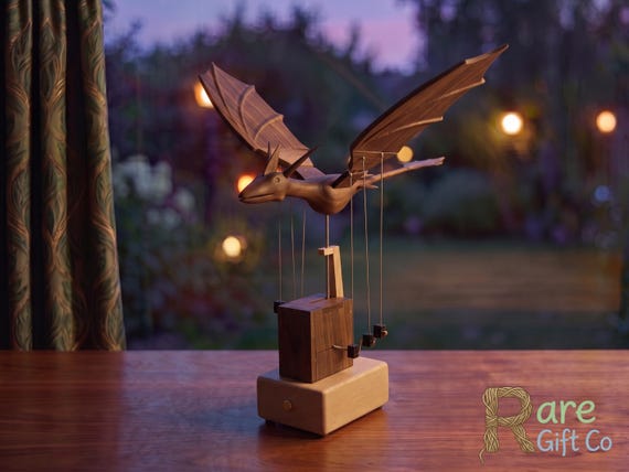 A hand-carved walnut dragon that actually MOVES — a mechanical automata sculpture that brings fantasy desk decor into a whole new dimension of craftsmanship.