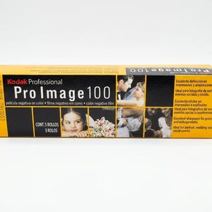 May include: A yellow and black Kodak Professional Pro Image 100 film box. The box contains 5 rolls of color negative film. The box has images of a young girl, a couple, and a group of people. The box also has text in English and Spanish.