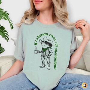funny frog cowboy st patricks day png, retro shenanigan frog shirt design, vintage western irish green frog, frog riding cowboy funny illustration, st paddys day green frog art, distressed green cowboy frog sublimation, whimsical irish shenanigan digital download, lucky frog cowboy hat western png, funny st patricks day humor for adults, vintage woodcut style frog cowboy design