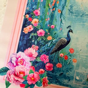 May include: A decorative scarf featuring a peacock standing amidst pink and orange flowers and lush greenery. The background depicts a blue waterfall and a serene landscape. The scarf is bordered by a pink frame with vertical stripes.
