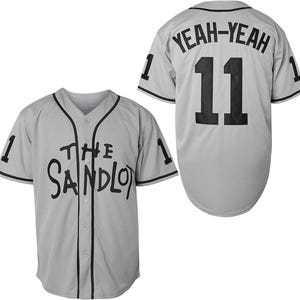 May include: A light gray baseball jersey with black trim and the text "THE SANDLOT" on the front. The back of the jersey has the number 11 and the text "YEAH-YEAH". The number 1 is on each sleeve.