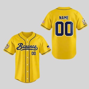 May include: Yellow baseball jersey with the word "Bananas" in navy blue script on the front, and the number "00". The back of the jersey has the word "NAME" above the number "00". The jersey has navy blue trim and a small American flag on the sleeve.