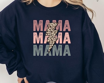 May include: Navy blue sweatshirt with the word "MAMA" repeated three times in pink, light pink, and gray. A leopard print lightning bolt graphic is centered over the word "MAMA". The word "Navy" is written in cursive in the upper right corner.