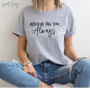 May include: A light gray t-shirt with the text "After all this time... Always" in black script. The shirt has short sleeves and is made of a soft material. The words "Sport Grey" are printed in script at the top left.
