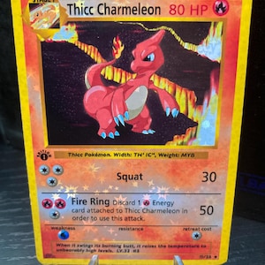Puede incluir: Una carta coleccionable de Pokémon Thicc Charmeleon con una ilustración de Charmeleon rojo y blanco. La tarjeta tiene un borde amarillo y presenta texto que incluye "Squat" y "Fire Ring". La tarjeta está en un soporte.